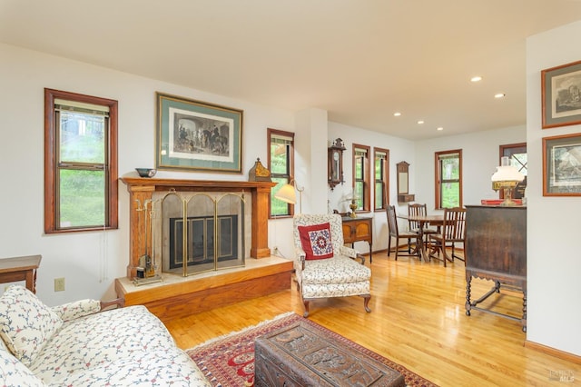 living area featuring recessed lighting, wood finished floors, and a glass covered fireplace