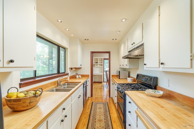 kitchen featuring butcher block counters, appliances with stainless steel finishes, white cabinetry, a sink, and under cabinet range hood