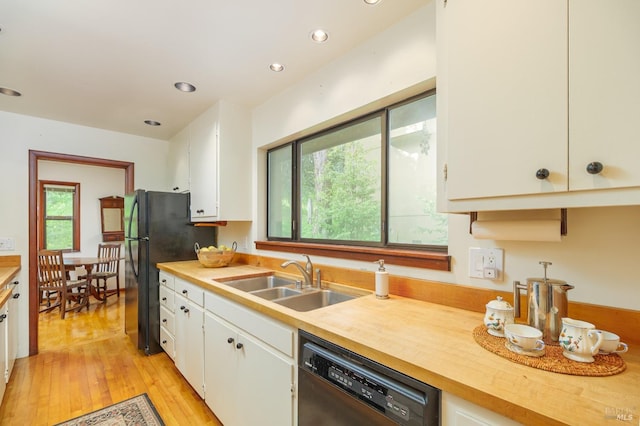 kitchen featuring black appliances, light wood-style flooring, white cabinets, and a sink