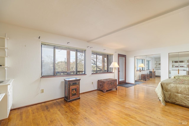 interior space featuring beam ceiling, baseboards, and wood finished floors