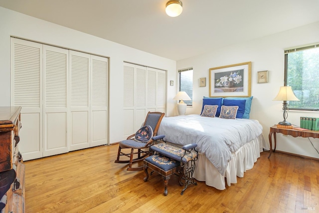 bedroom with radiator heating unit, two closets, and light wood-style floors