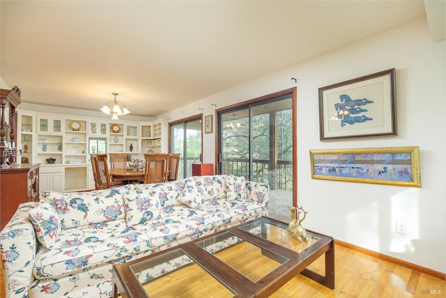 living room featuring baseboards, a chandelier, and wood finished floors