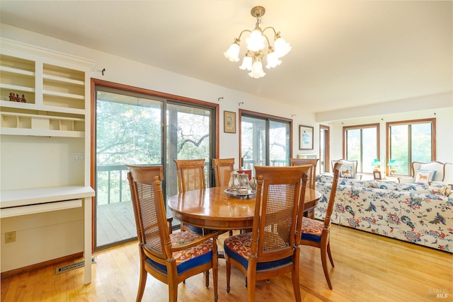 dining space featuring light wood-style floors and a notable chandelier