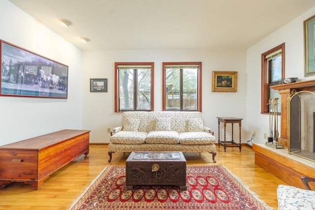 living area featuring a high end fireplace, baseboards, and wood finished floors