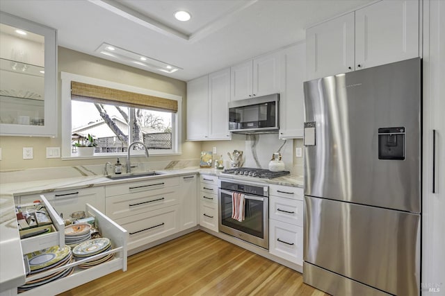 kitchen featuring white cabinetry, appliances with stainless steel finishes, sink, and light stone counters