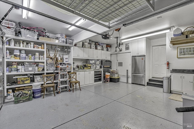 garage featuring a garage door opener, beverage cooler, and stainless steel refrigerator