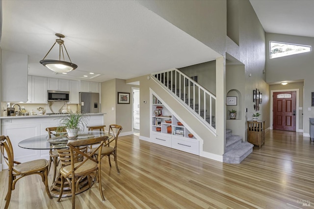 dining space featuring sink, a high ceiling, and light wood-type flooring