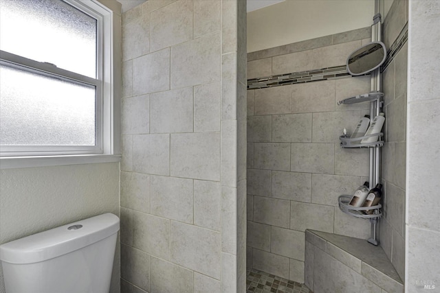 bathroom with toilet and tiled shower