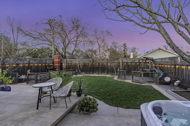 yard at dusk featuring a playground and a patio