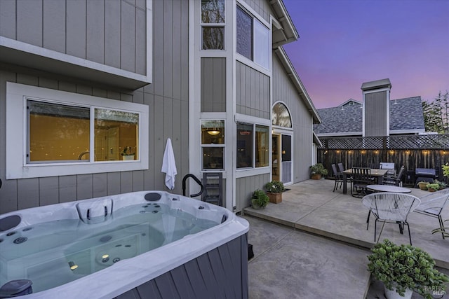 patio terrace at dusk featuring a hot tub