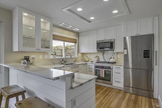 kitchen featuring white cabinetry, sink, a kitchen breakfast bar, kitchen peninsula, and stainless steel appliances