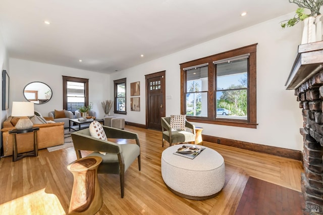 living area with light wood finished floors, a fireplace, baseboards, and recessed lighting