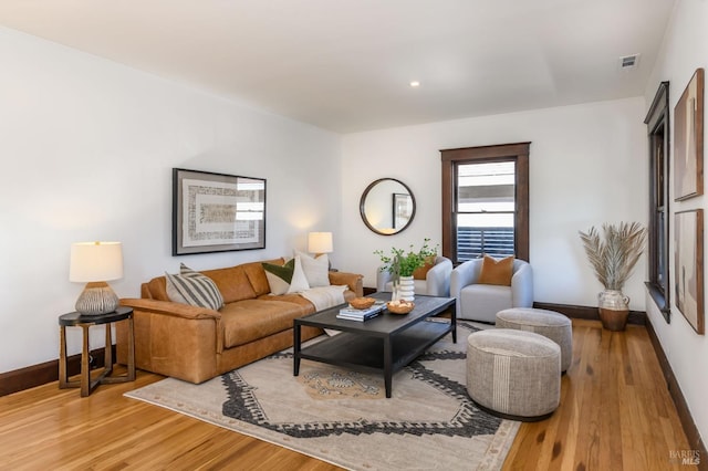 living area featuring wood finished floors, visible vents, and baseboards