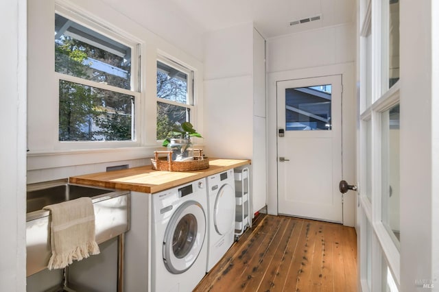 clothes washing area with laundry area, washer and clothes dryer, wood finished floors, and visible vents