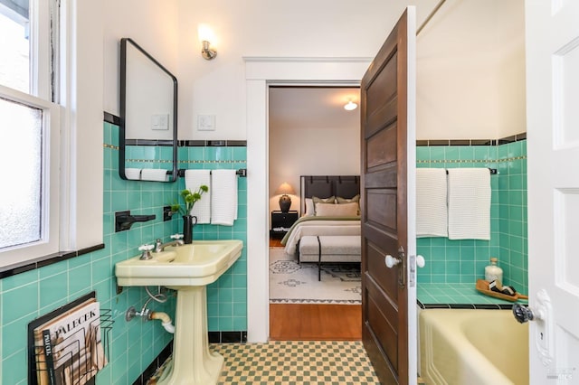 bathroom featuring a bath, a wainscoted wall, connected bathroom, and tile walls