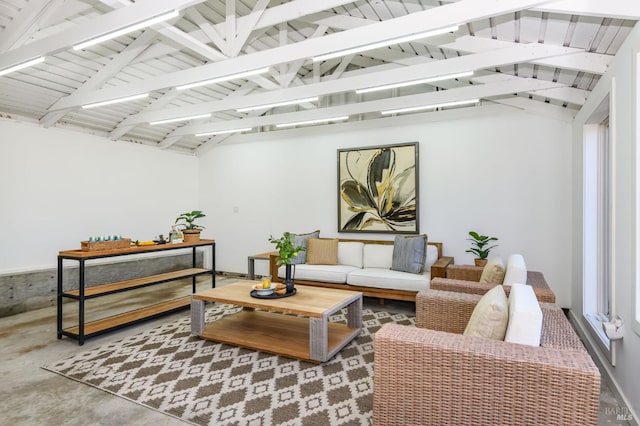 living area featuring vaulted ceiling with beams and concrete floors