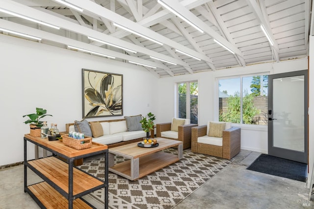 living room featuring concrete flooring, beam ceiling, high vaulted ceiling, and baseboards