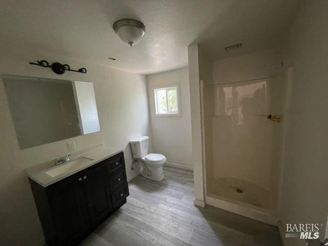 bathroom with walk in shower, vanity, toilet, and hardwood / wood-style flooring