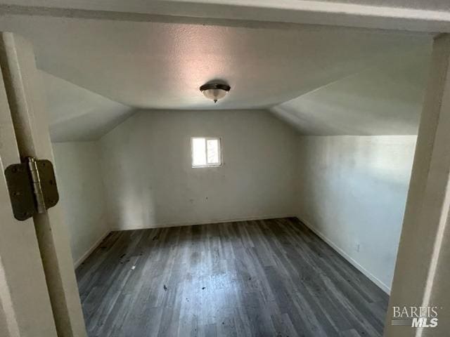 additional living space with dark hardwood / wood-style flooring and vaulted ceiling