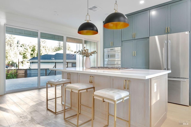 kitchen featuring light hardwood / wood-style flooring, a breakfast bar area, blue cabinets, and appliances with stainless steel finishes