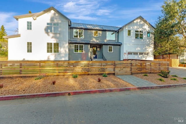 view of front facade with metal roof, a standing seam roof, and a fenced front yard