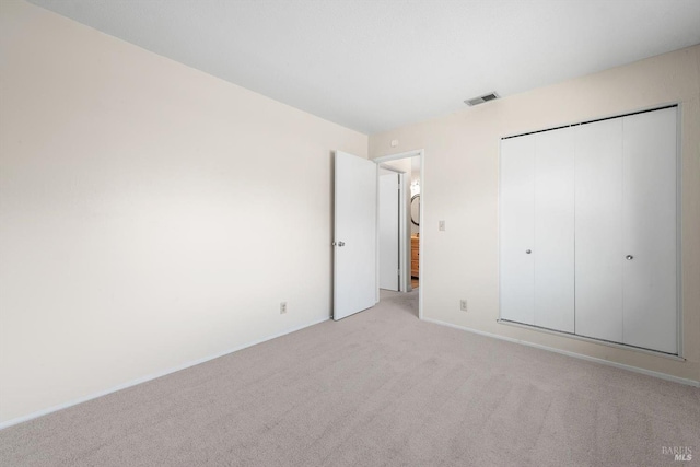 unfurnished bedroom with light colored carpet and a closet