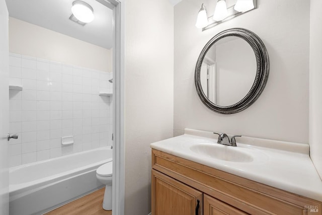 full bathroom with vanity, hardwood / wood-style flooring, tiled shower / bath combo, and toilet