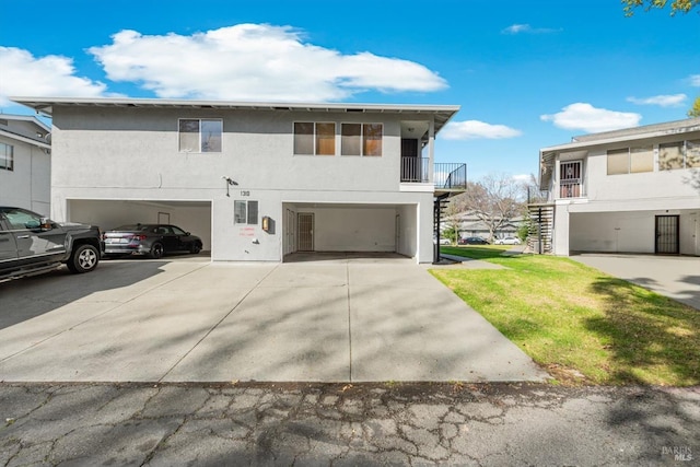 view of front facade featuring a garage, a balcony, and a front yard