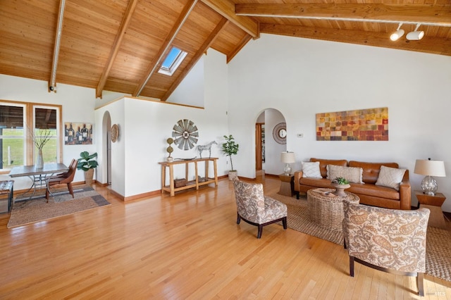 living room featuring high vaulted ceiling, a skylight, beamed ceiling, hardwood / wood-style flooring, and wooden ceiling