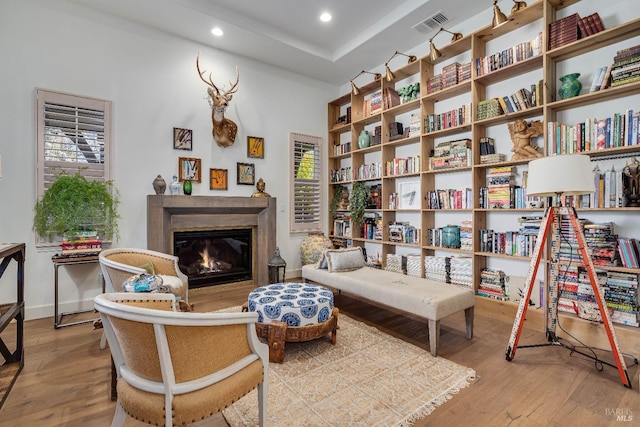 living area featuring a glass covered fireplace, visible vents, recessed lighting, and wood finished floors