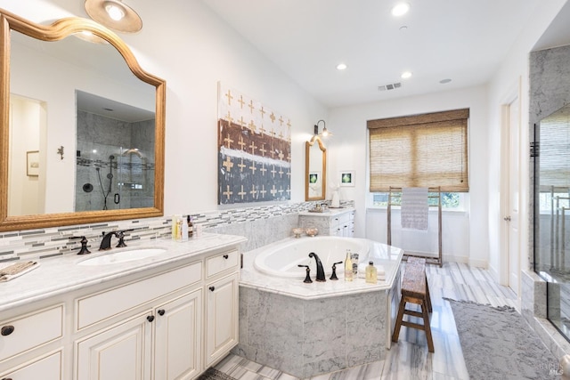 full bath featuring a stall shower, visible vents, two vanities, a sink, and a bath