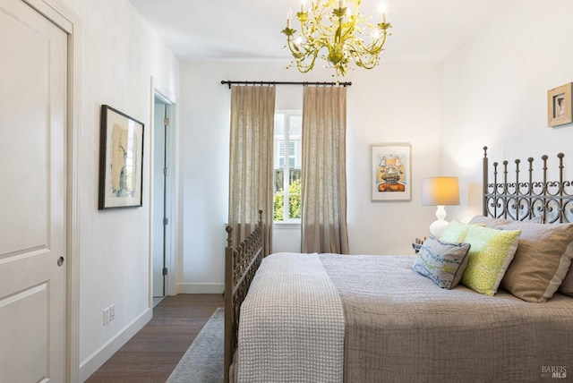 bedroom featuring baseboards, an inviting chandelier, and wood finished floors