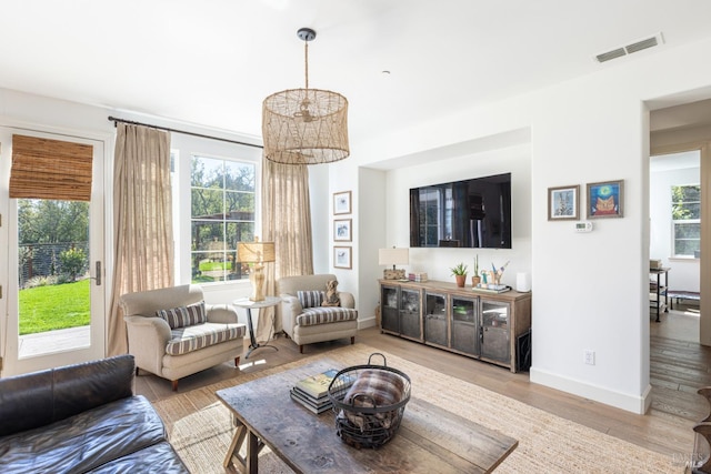 living area with an inviting chandelier, wood finished floors, visible vents, and baseboards