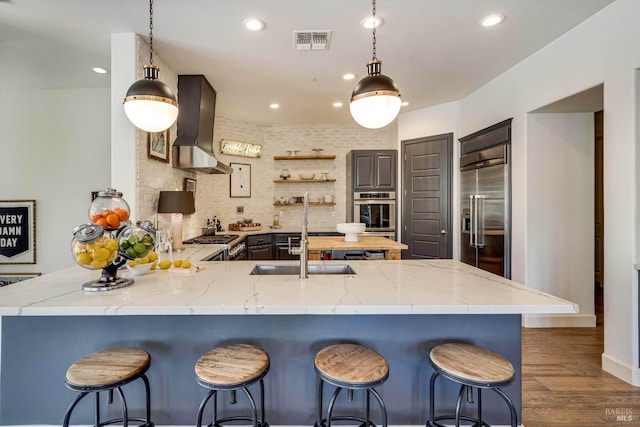 kitchen featuring visible vents, appliances with stainless steel finishes, decorative light fixtures, a peninsula, and open shelves