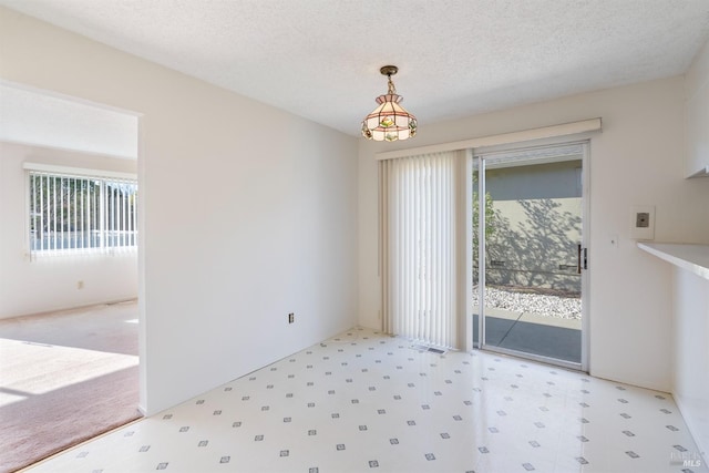 unfurnished dining area featuring a textured ceiling