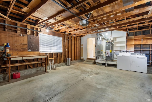 basement featuring washer and dryer, heating unit, water heater, and a workshop area