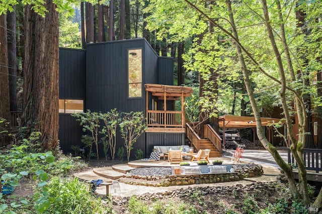 back of property featuring a patio and an outdoor living space with a fire pit