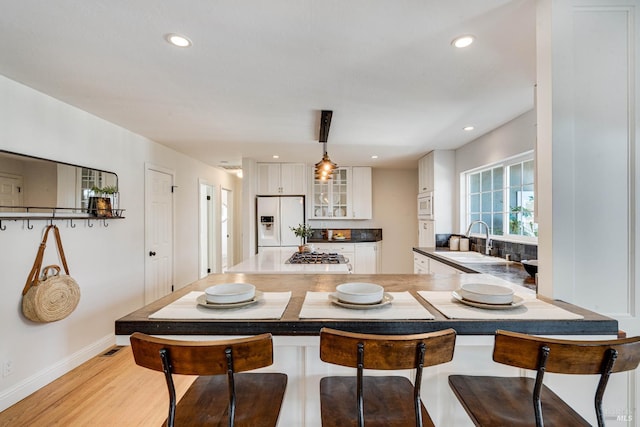 1077 Valley View St, Saint Helena, CA 94574 - kitchen featuring white appliances, a peninsula, white cabinets, glass insert cabinets, and a kitchen bar