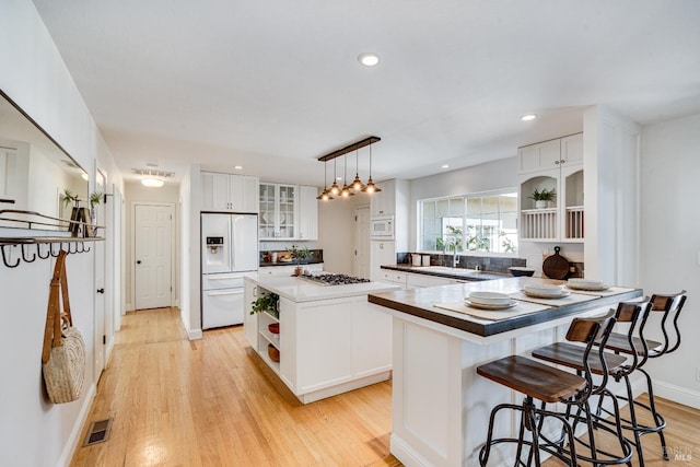 1077 Valley View St, Saint Helena, CA 94574 - kitchen featuring open shelves, white appliances, a center island, a kitchen bar, and glass insert cabinets