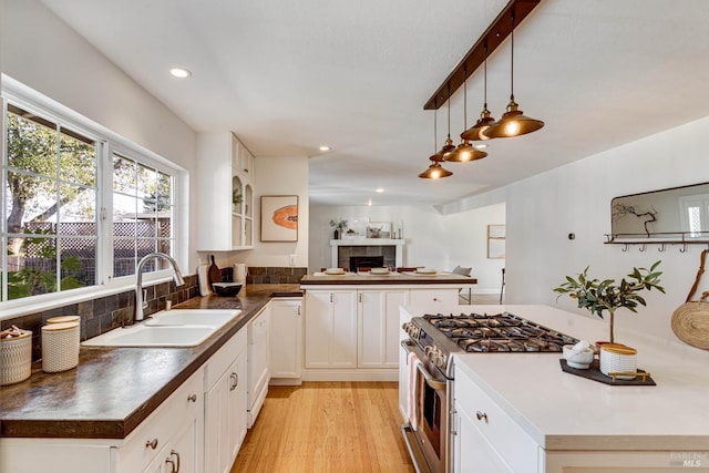 1077 Valley View St, Saint Helena, CA 94574 - kitchen featuring stainless steel gas stove, a tiled fireplace, dark countertops, recessed lighting, and white cabinetry
