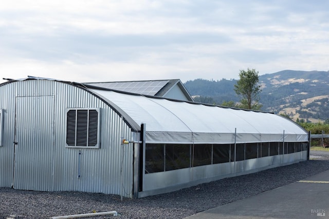 view of side of property with a mountain view and an outbuilding