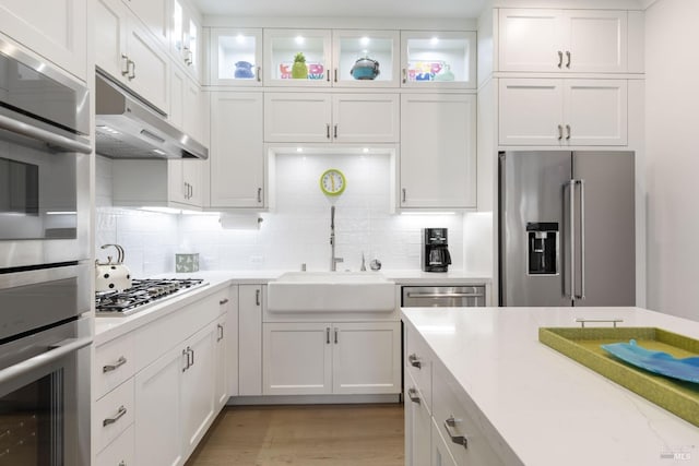 kitchen with tasteful backsplash, sink, white cabinets, and appliances with stainless steel finishes