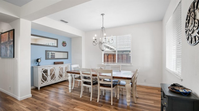 dining area featuring visible vents, an inviting chandelier, baseboards, and wood finished floors