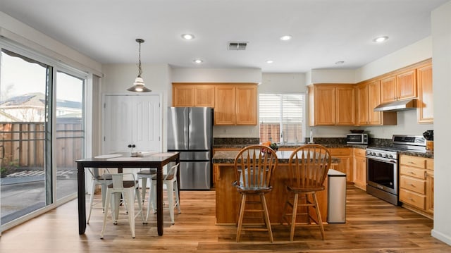 kitchen with a center island, under cabinet range hood, recessed lighting, light wood-style floors, and stainless steel appliances