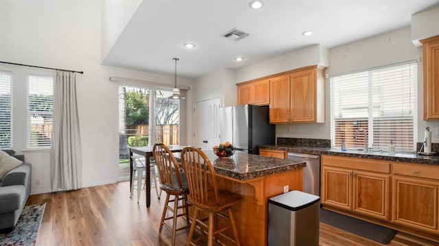 kitchen featuring visible vents, a healthy amount of sunlight, a kitchen island, appliances with stainless steel finishes, and a sink