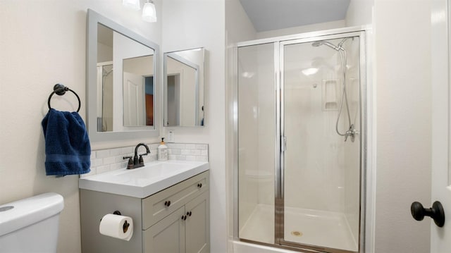 bathroom featuring vanity, toilet, a stall shower, and backsplash