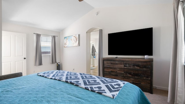 bedroom featuring ensuite bathroom, carpet floors, arched walkways, baseboards, and vaulted ceiling