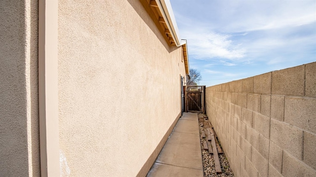 view of home's exterior with a gate, stucco siding, and fence