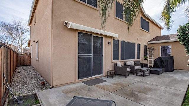 rear view of property with an outdoor living space, stucco siding, a fenced backyard, and a patio area