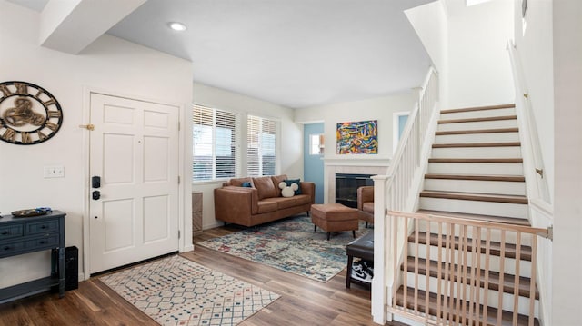 entrance foyer with recessed lighting, a fireplace, stairs, and wood finished floors